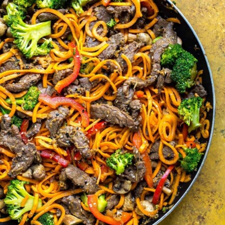 A close-up of ginger beef stir fry with sweet potato noodles.