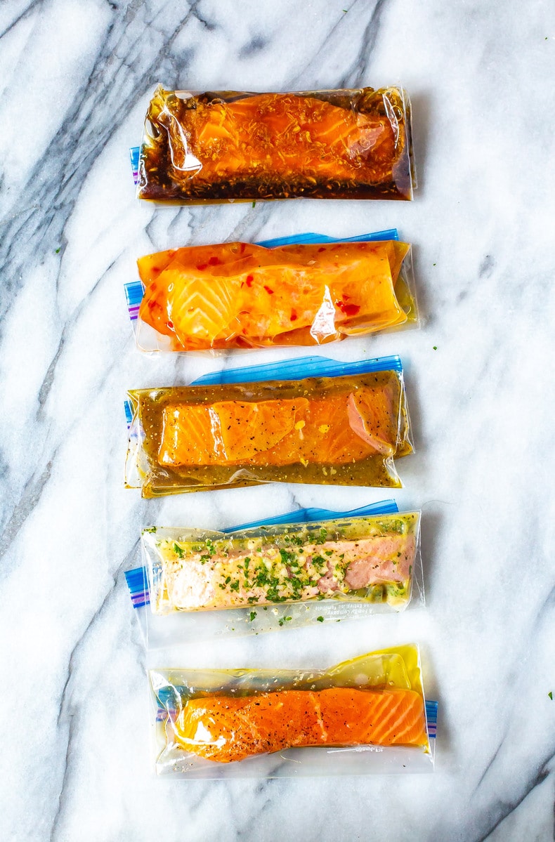 Five freezer bags with marinated salmon filets in five different marinades: Teriyaki, Chili Lime, Maple Dijon, Lemon Garlic and Plain.