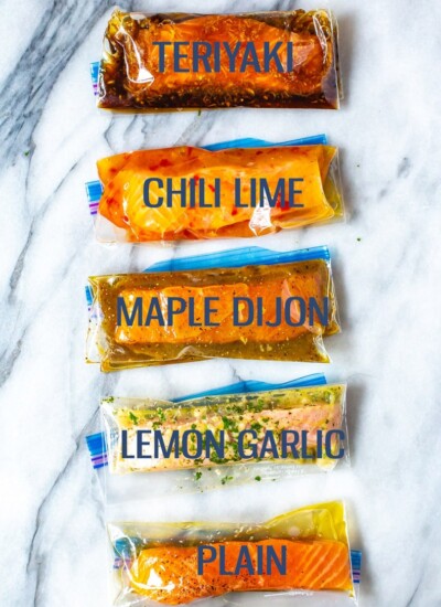 Five freezer bags with marinated salmon filets, labelled "Teriyaki", "Chili Lime", "Maple Dijon", "Lemon Garlic" and "Plain".