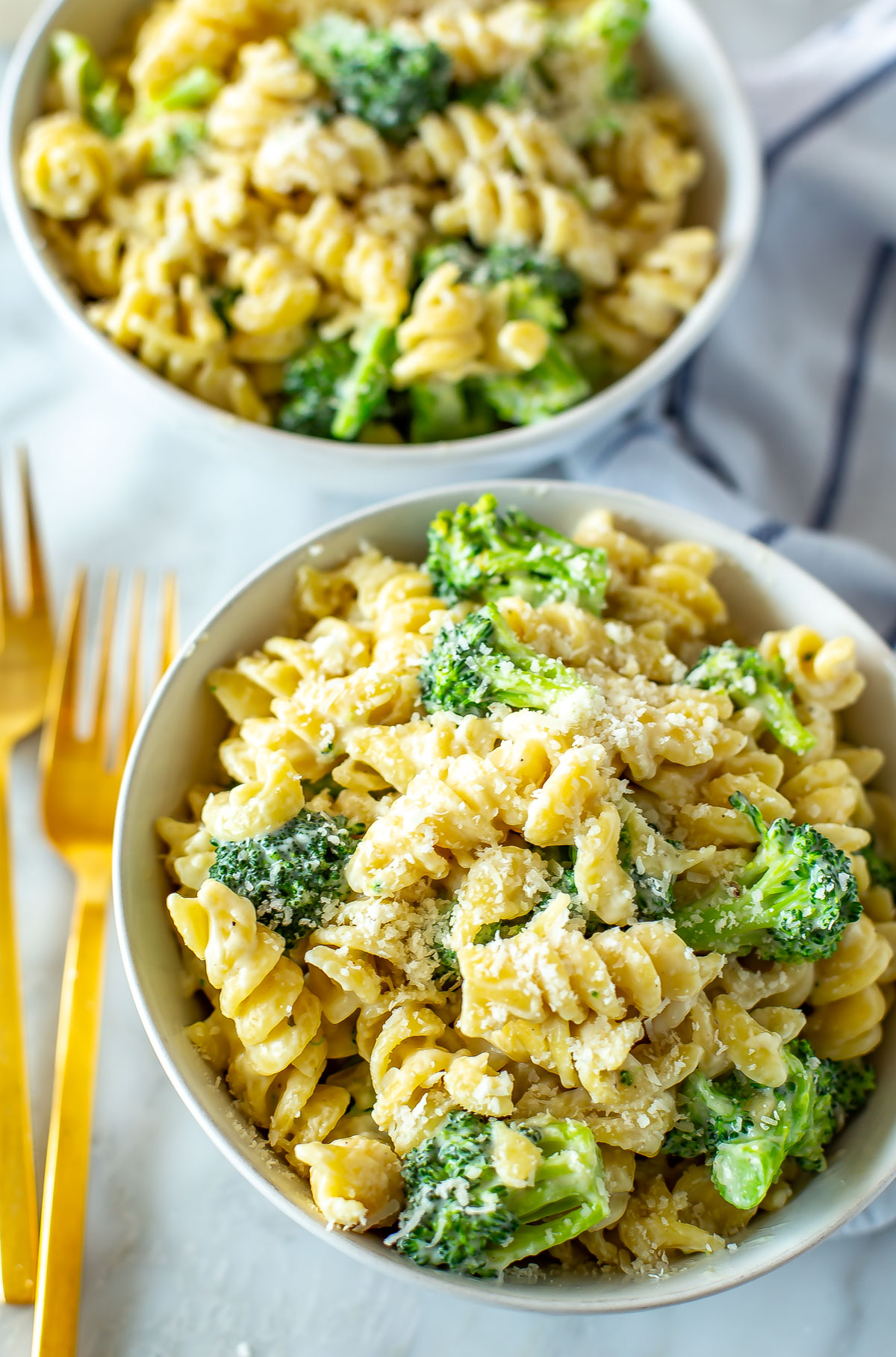 A close-up of two bowls of broccoli alfredo pasta.