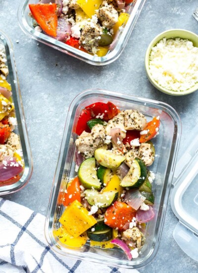 A close-up of two meal prep containers filled with sheet pan Greek chicken meal prep bowls.