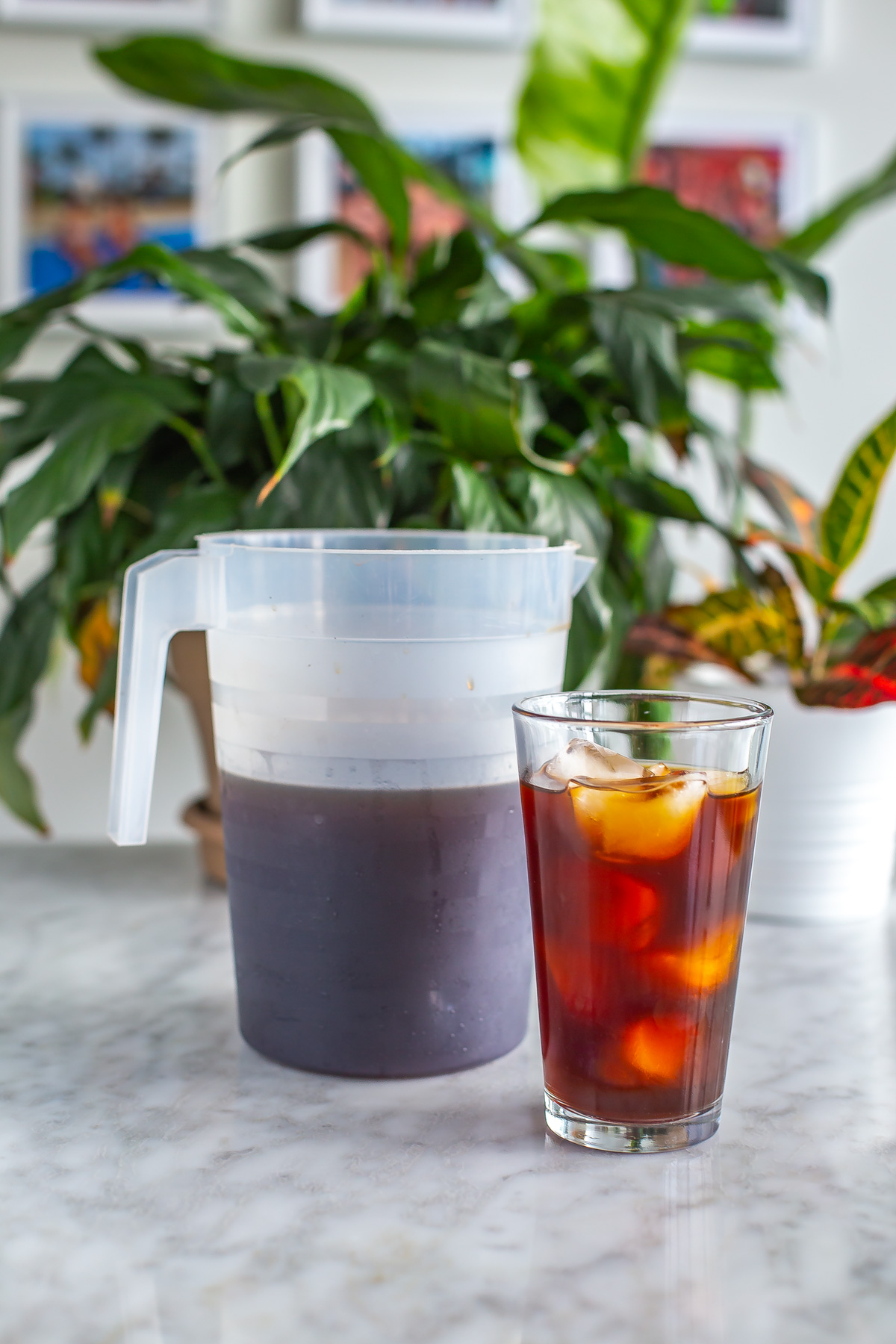 A pitcher of cold brew coffee next to a class of black cold brew coffee with ice.