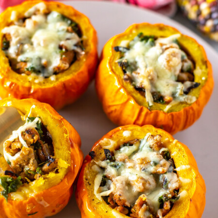 Four stuffed mini pumpkins on a platter with fall core in the background.