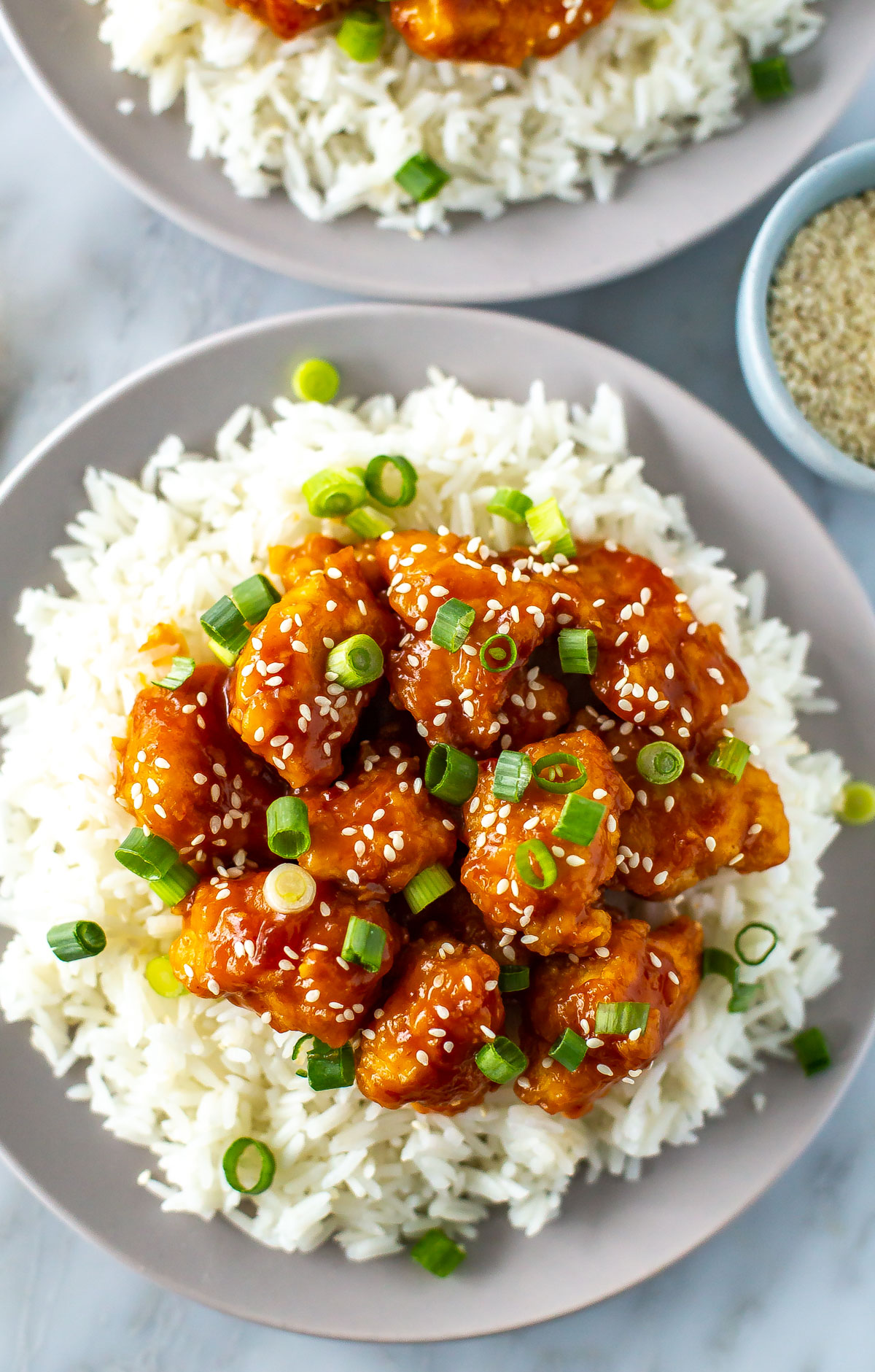 A close-up of crispy mandarin chicken on a plate of rice.