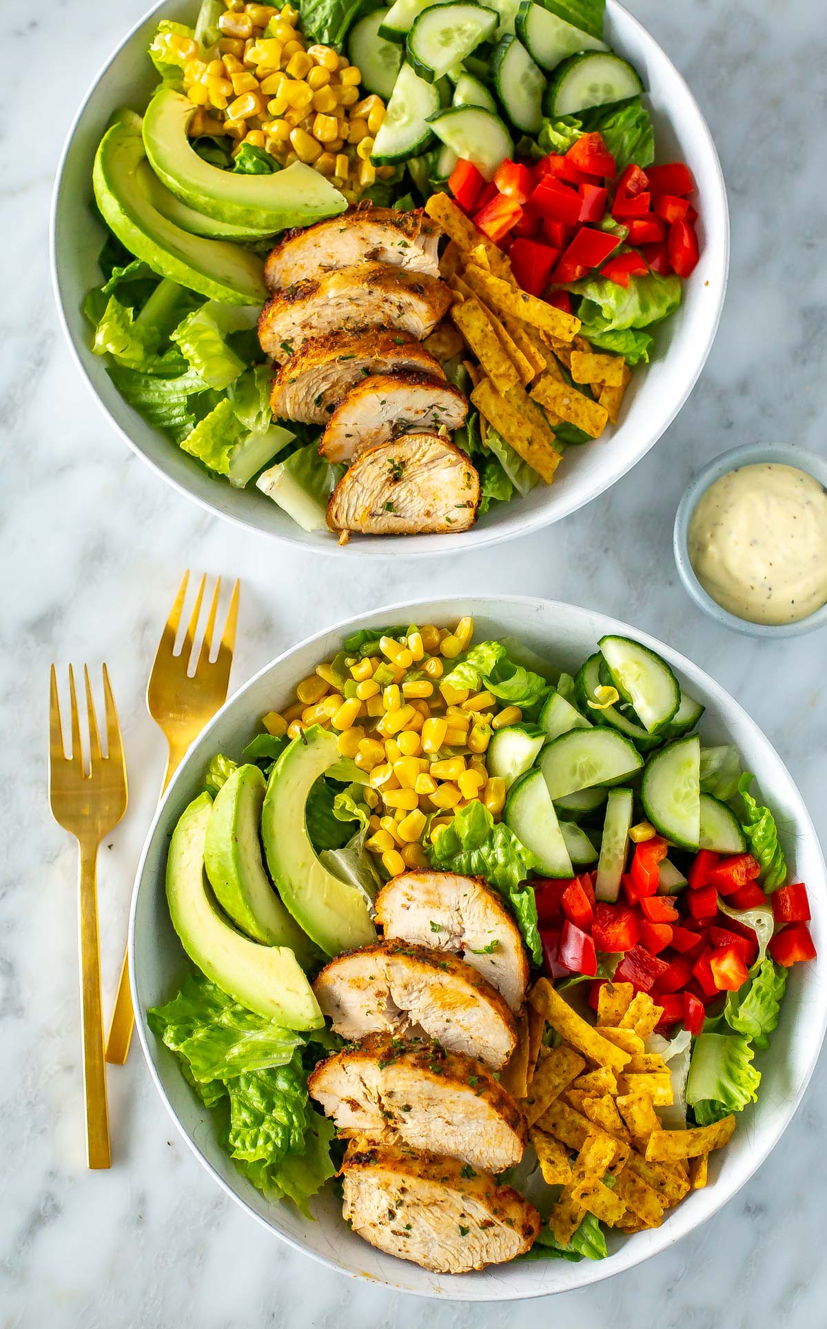 Two bowls of salad with sliced air fryer chicken breasts on top.