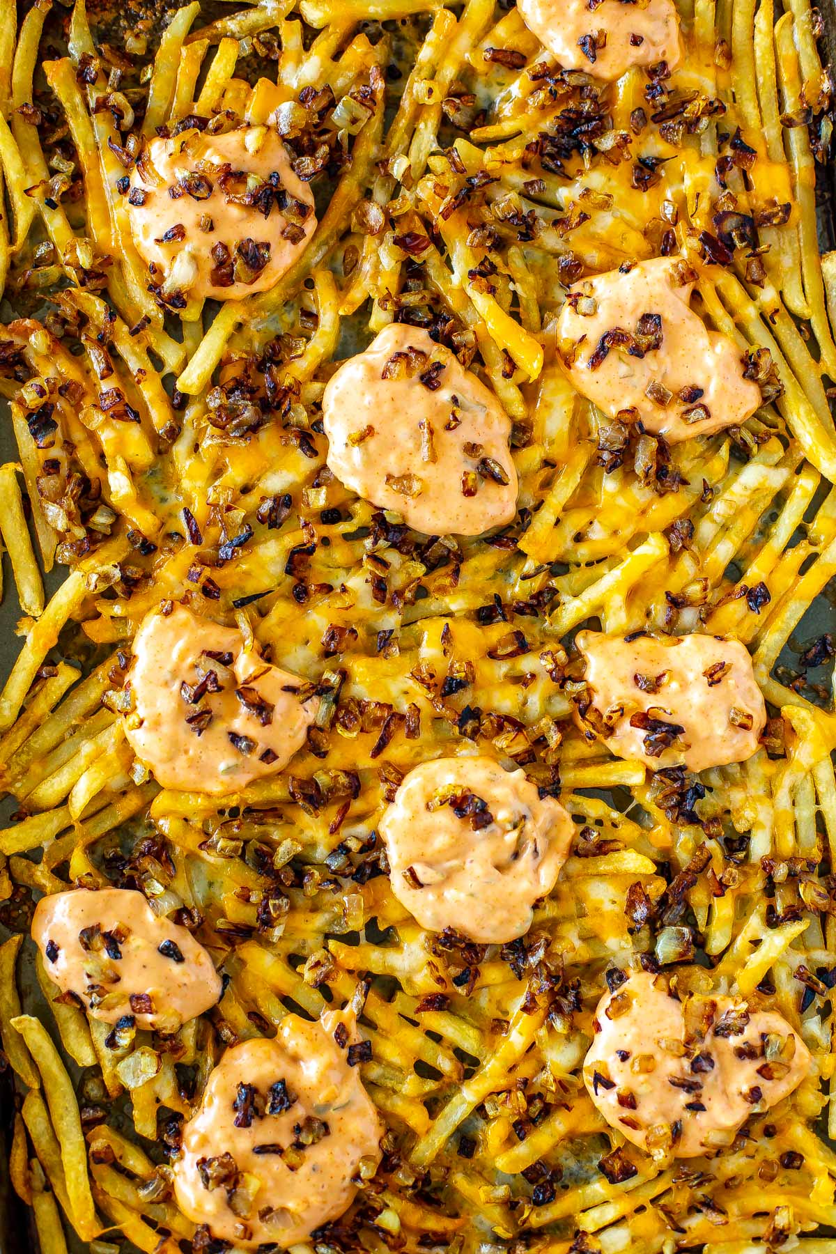 A close-up of animal style fries on a sheet pan.