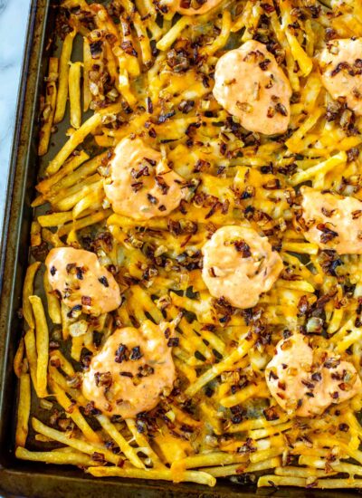 A sheet pan with animal style fries on it.