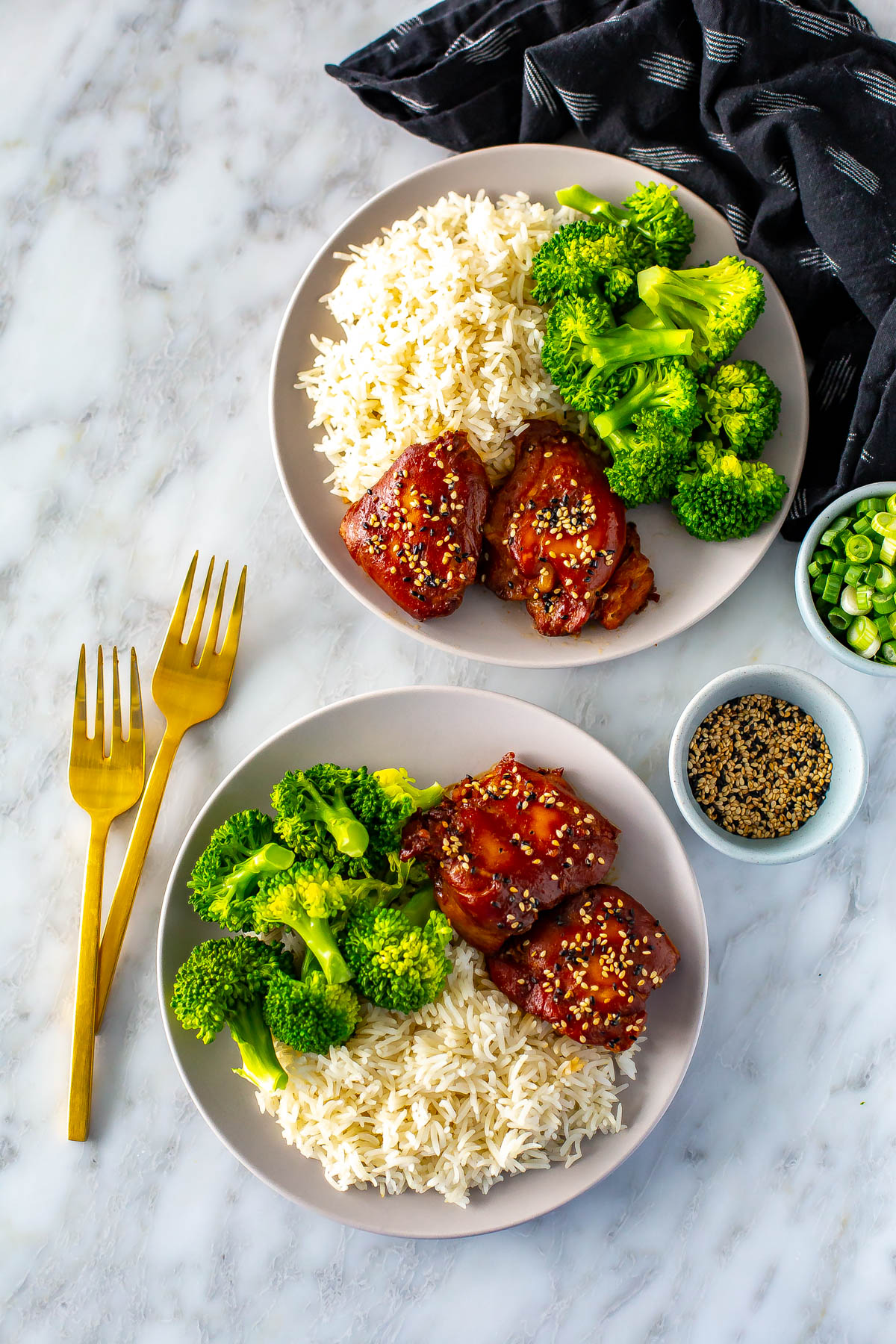 Two plates with slow cooker honey garlic chicken thighs served with broccoli and rice.