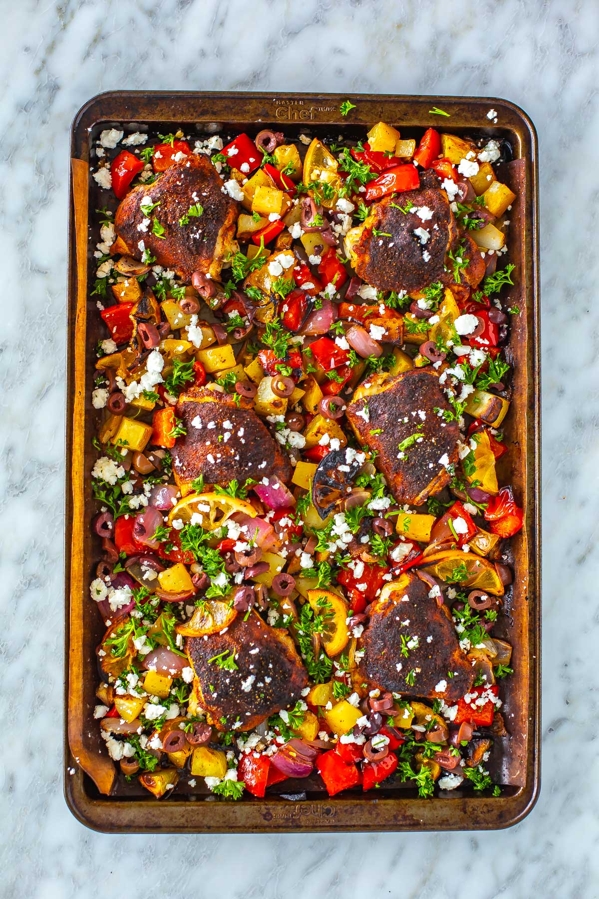 A sheet pan of baked chicken thighs and vegetables.