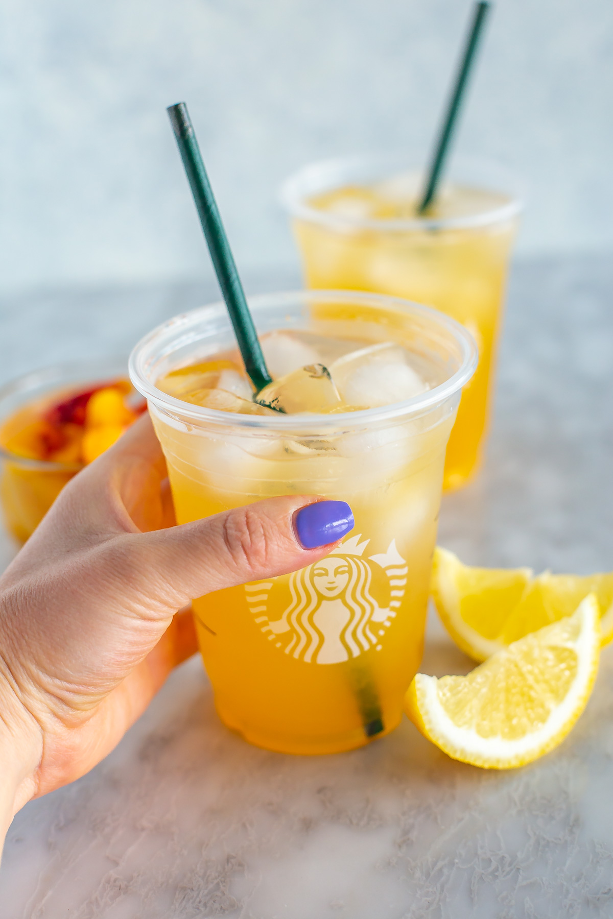 A hold holding a copycat Starbucks iced peach green tea lemonade.