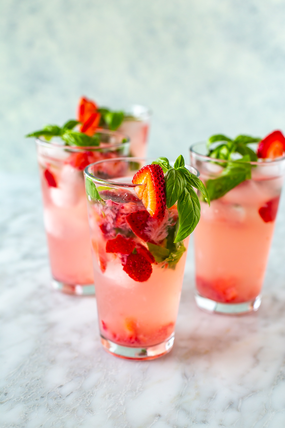 Tall glasses filled with strawberry basil fizz.