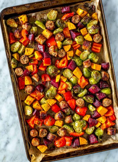 A sheet pan with sausage and vegetables.