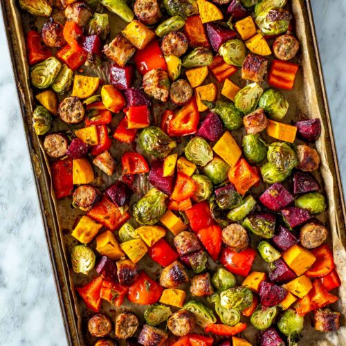 A sheet pan with sausage and vegetables.