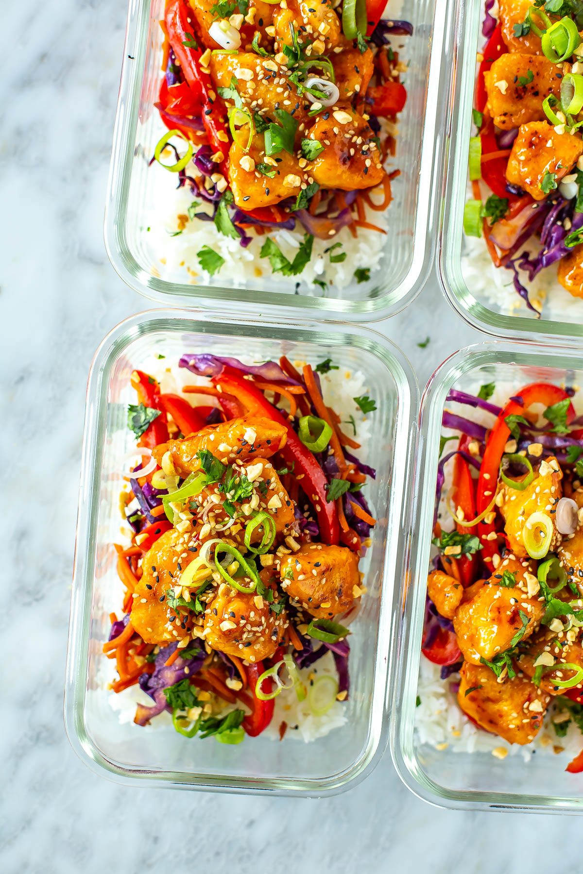 Four meal prep containers, each with a serving of sweet chili chicken.