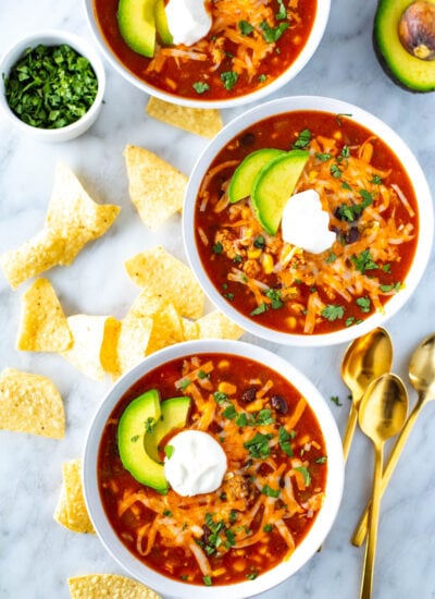 Three bowls of southwest chili topped with sour cream.